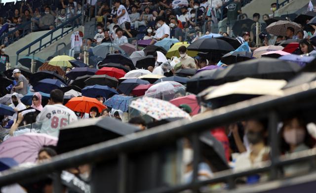 4일 오후 서울 송파구 잠실야구장에서 프로야구 경기를 지켜보던 관중들이 갑작스레 내린 비에 우산을 펴고 있다. 뉴스1