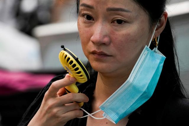 중국 상하이에서 한 여성이 잠시 마스크를 벗은 채 휴대용 선풍기로 바람을 쐬고 있다. 상하이=로이터 연합뉴스