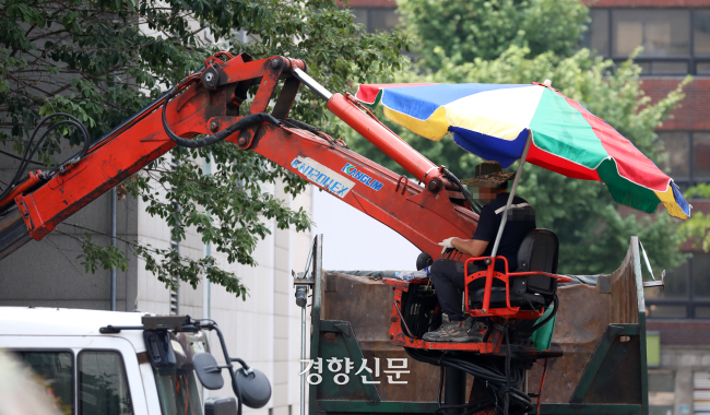 서울 시내 한 건설현장에서 한 노동자가 파라솔을 치고 크레인 위에서 작업을 하고 있다. / 권도현 기자