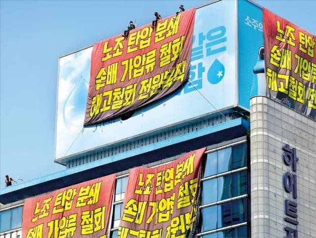 < 점점 더 과격해지는 화물연대 > 16일 서울 청담동 하이트진로 본사를 불법 점거한 전국민주노동조합총연맹 공공운수노조 화물연대 조합원들이 회사 대형 옥외 광고판에 요구사항이 적힌 현수막을 내건 채 시위하고 있다. 연합뉴스