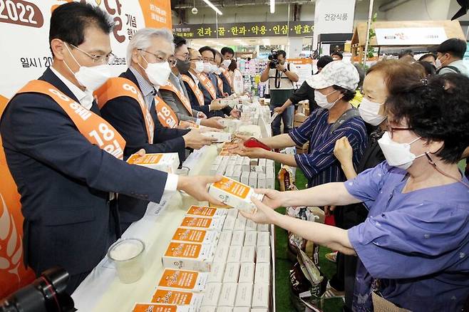 18일 서울 서초구 농협 하나로마트 양재점에서 열린 '2022년 제8회 쌀의 날 기념행사'에서 나병만 농협양곡 대표(왼쪽) 등 참석자들이 방문객에게 쌀 품종세트를 나눠주고 있다.
