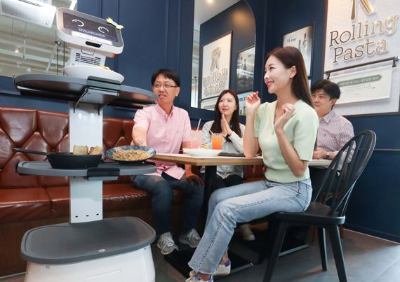 LG유플러스는 LG전자와 함께 로봇사업을 본격 추진하고 서빙-배송-안내 등 고객 접점에서 디지털혁신을 가속화한다고 22일 밝혔다. 사진은 서울 구로구 롤링파스타 매장에서 LG 클로이 서브봇이 가져온 음식을 손님이 꺼내는 모습. LG유플러스 제공