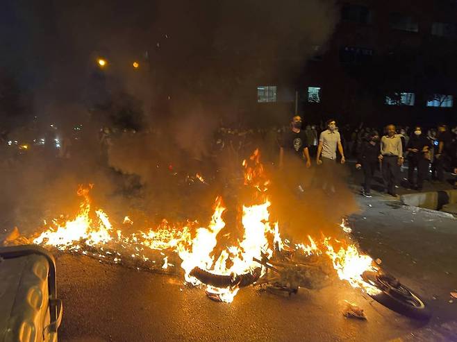 19일(현지시간) 이란 테헤란 시내에서 복장 규정 위반으로 구금됐던 여성이 숨진 것에 항의하는 시위대가 경찰 오토바이를 불에 태우고 있다. /AP=뉴시스