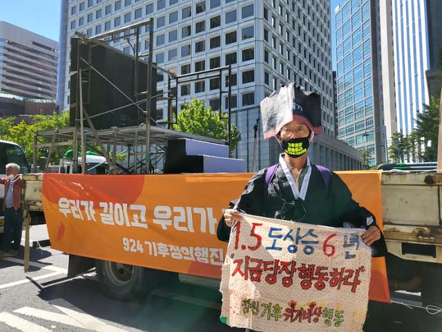 박종권씨가 24일 오후 서울 시청역 근처에서 천으로 만든 팻말을 들고 기후정의행진을 하고 있다. 강지수 기자.