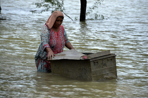 8월 25일(현지시간) 파키스탄 남서부 발루치스탄 주의 자프라바드에서 한 여성이 홍수 피해를 입은 집에서 쓸 수 있는 물건들을 건져내기 위해 여행용 가방을 물 위로 옮기고 있다. 파키스탄 정부는 올 석달 가까이 이어진 폭우로 큰 피해를 입자 국제 사회의 지원을 요청했다. 자프라바드 AP 뉴시스.jpg