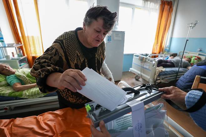 26일(현지 시각) 러시아군이 점령한 우크라이나 동부 도네츠크의 한 병원에서 한 시민이 투명한 투표함에 접히지 않은 투표용지를 넣고 있다. /타스 연합뉴스