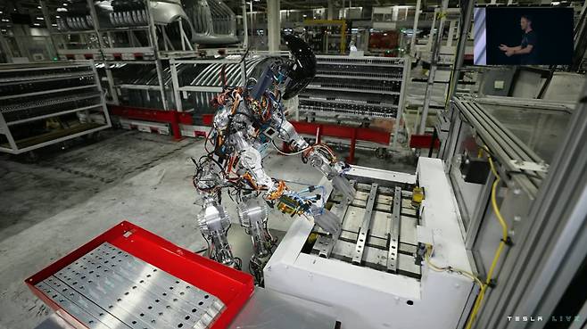 30일(현지시각) 테슬라가 공개한 영상 속 로봇의 모습. 테슬라 봇이 손으로 차체 부품을 옮기고 있다. /테슬라 행사 캡처