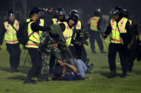<yonhap photo-2298=“”> Security o</yonhap> - Security officers detain a fan during a clash between supporters of two Indonesian soccer teams at Kanjuruhan Stadium in Malang, East Java, Indonesia, Saturday, Oct. 1, 2022. Clashes between supporters of two Indonesian soccer teams in East Java province killed over 100 fans and a number of police officers, mostly trampled to death, police said Sunday. AP 연합뉴스