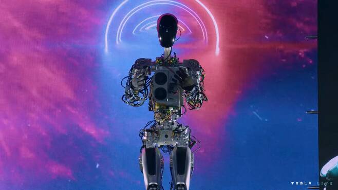 지난 1일(현지시간) 테슬라가 ‘AI데이2’에서 공개한 인공지능 로봇 ‘옵티머스’가 두 손을 가슴에 모은 채 등장하고 있다. 테슬라 실시간 중계 화면 캡처