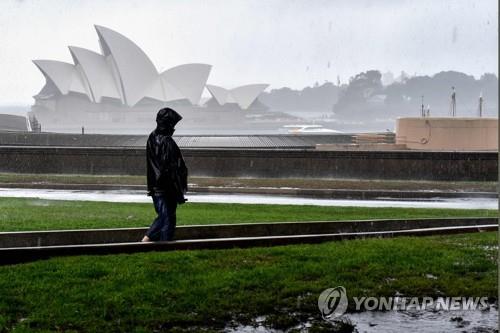 집중호우 계속되는 호주 시드니     (시드니 AFP=연합뉴스) 6일(현지시간) 호주 시드니에서 비가 내리는 가운데 한 여성이 오페라 하우스 앞을 걸어가고 있다. 2022.10.06