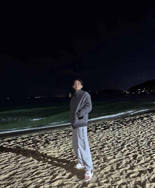 BTS member Vs smile lit up the night sea of Busan.On the 25th, V posted a picture on his instagram with a short article called  ⁇ Busan  ⁇ .BTS Concert  ⁇  BTS  ⁇  Yet To Come  ⁇  in BUSAN  ⁇  It seems that the photo was taken on the 15th. A brilliant smile revealed the night sea of Busan.V also left a mirror selfie in the costume he wore on the concert stage, reminiscent of the memories of the Busan Concert with his fans.V walked barefoot on the sandy beach at Busan night, leaving a mirror selfie at the hostel.