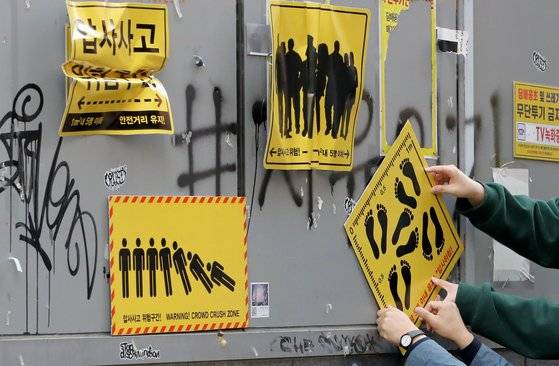 10일 서울 마포구 홍익대 정문 인근 골목에서 시민활동가들이 이제석 광고연구소가 제작한 압사 사고 위험구간 표지판을 시범 부착하고 있다. 뉴스1