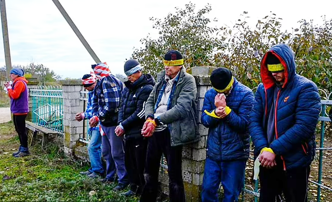 남성 8명이 모자와 테이프 등으로 눈이 가려지고 손이 묶인 채 우크라이나 헤르손 대로변에 서 있는 모습을 담고 있다. 이들은 러시아군 점령 당시 그들에게 협력한 혐의를 받고 있다