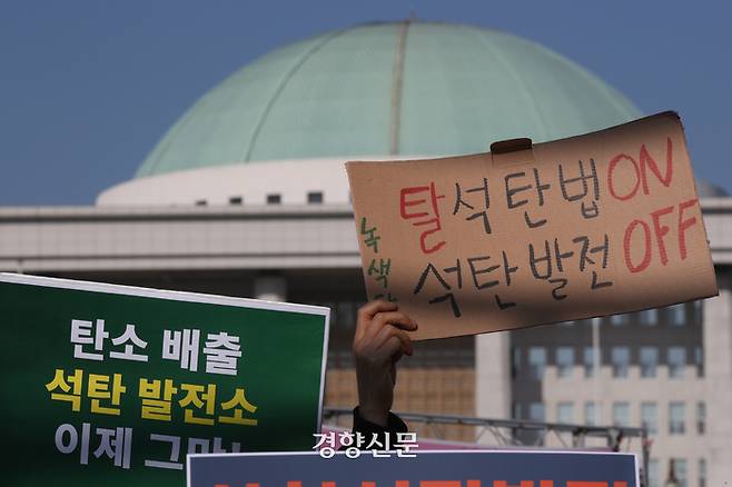 환경운동연합 등 환경단체 회원들이 23일 서울 국회 앞에서 열린 기자회견에서 삼척 석탄발전 최초 점화 중단과 탈석탄법 제정을 촉구하는 손팻말을 들고 있다. 성동훈 기자