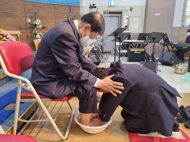 김필수(오른쪽) 목사가 지난 11일 전북 군산 비전교회에서 열린 '호남특별연회 원로목사 부부 초청 위로회’에서 한 은퇴 목회자의 발을 씻겨주며 기도를 하고 있다. 비전교회 제공