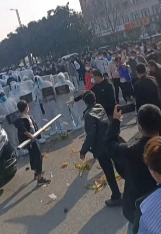 중국 허난성 정저우에 있는 폭스콘 공장에서 지난 23일 노동자들이 방호복을 입고 방패를 든 경찰과 대치하고 있는 모습이 영상이 담겨 있다. AFP연합뉴스