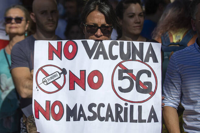 스페인 마드리에서 집회 참가자가 “백신 반대, 5G 반대, 마스크 반대”라는 구호가 적힌 손팻말을 들고 있다. 코로나19 부정론자들은 코로나 바이러스가 5G 기지국 때문에 생겼다는 등의 음모론을 믿는다. AP 연합뉴스
