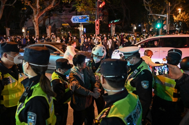중국 상하이의 위구르인 거주지 우루무치중루에서 27일 밤 한 시민이 경찰에 연행되고 있다. 이곳에서는 전날 밤부터 새벽까지 코로나19 봉쇄에 항의하는 시민 수천명이 모여 “시진핑 물러나라” “공산당 물러나라” 등의 구호를 외쳤다. 이날에도 시민들이 모여들 조짐을 보이자 경찰이 거리를 통제했고, 일부 시민을 연행하기도 했다.  AFP연합뉴스