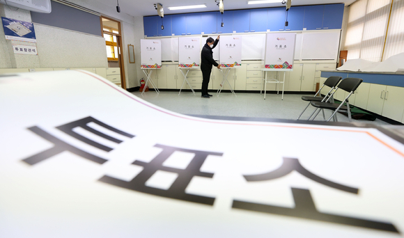 서울 시내 한 초등학교에 마련된 투표소에서 구청 및 주민센터 직원들이 기표소를 설치하고 있다.  [사진=뉴시스]