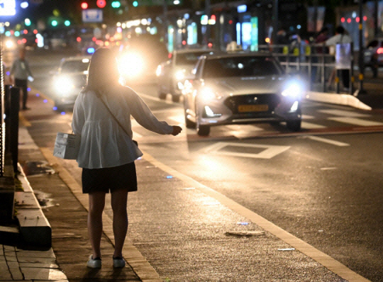 심야에 서울 시내에서 한 시민이 도로에 나와 택시를 잡고 있는 모습. 자료사진