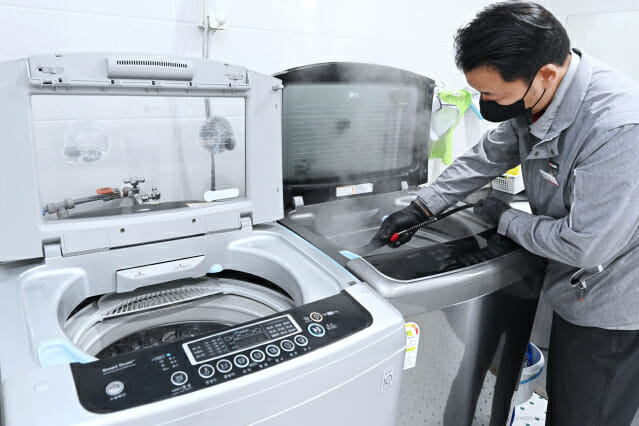 LG전자 직원이 사회복지시설에서 세탁통에 스팀을 분사하는 통살균 서비스를 진행하고 있다.(사진=LG전자)