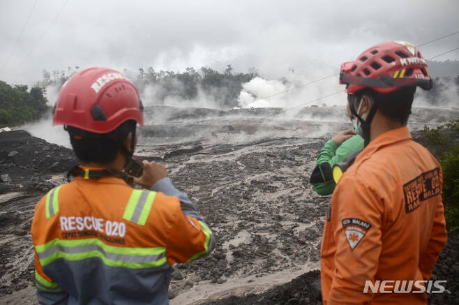 [자바섬=AP/뉴시스] 4일 인도네시아 동자바섬 스메루산 화산이 1년 만에 대규모로 재분화한 가운데 구조대원들이 화산 흐름을 지켜보고 있다. 2022.12.04.