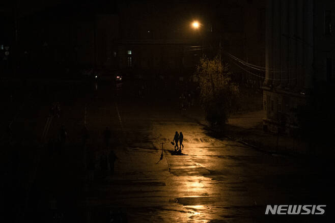 [키이우=AP/뉴시스] 지난달 6일(현지시간) 우크라이나 키이우에 순환 정전이 시행되는 동안 주민들이 캄캄한 거리를 걷고 있다.