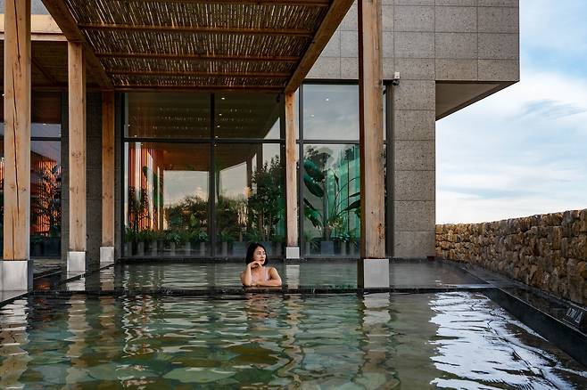 워터하우스 한편의 노천탕. 돌담으로 둘러싸여 있다. 돌담 너머에 기장 앞바다가 있다.