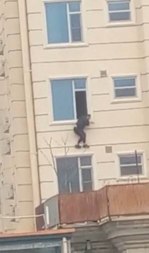 12일(현지시간) 아프가니스탄 수도 카불의 한 호텔에서 무장괴한의 공격이 발생한 가운데 투숙객으로 보이는 남성이 창밖으로 뛰어내릴 준비를 하고 있다. 로이터·연합뉴스