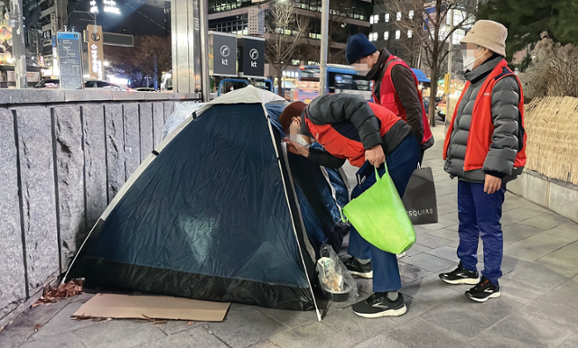 브릿지센터 상담원들이 8일 오후 8시 30분쯤 서울 을지로입구역 앞에서 노숙인 거리상담을 진행하고 있다. 노숙인들은 대개 침낭 밖으로 팔만 뻗어 동절기 키트를 받고는 다시 잠에 들었다. 최은서 기자