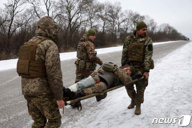 지난 14일(현지시간) 도네츠크주 솔레다르 인근 도로에서 부상한 우크라이나 병사가 들것에 실려 이동하고 있는 모습. 2023.01.14/뉴스1 ⓒ AFP=뉴스1 ⓒ News1 김민수 기자