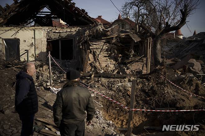 [키이우=AP/뉴시스]지난 2일(현지시간) 우크라이나 키이우에서 주민들이 러시아군의 공격으로 손상된 집들을 바라보고 있다. 2023.01.25
