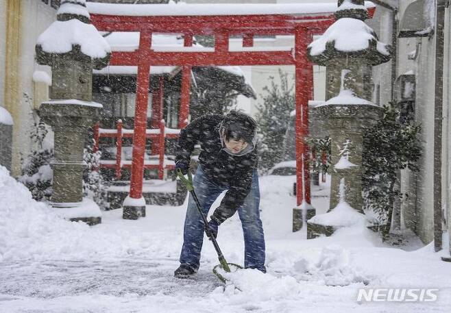 [돗토리=AP/뉴시스] 25일 일본 서부 돗토리현에서 한 남성이 신사 앞에 쌓인 눈을 치우고 있다. 기록적인 한파와 폭설이 일본 대부분 지역에 영향을 미쳐 고속도로, 항공, 기차 여행에 차질을 빚었고 더 많은 눈과 추위가 예보됐다. 2023.01.25