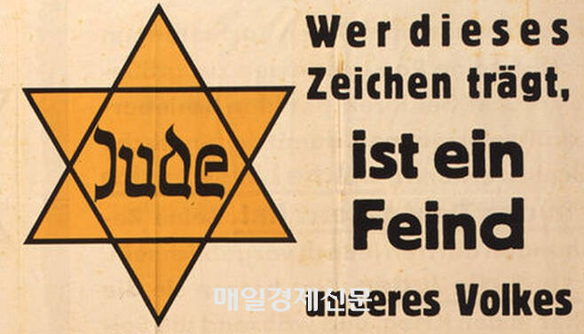 나치가 유대인에게 강요한 노란색 별 뱃지. 옆에 독일어는 “누구든지 이 표식을 달고 있는 사람은 우리 국민의 적입니다”를 뜻한다. 1942년 7월 사진.