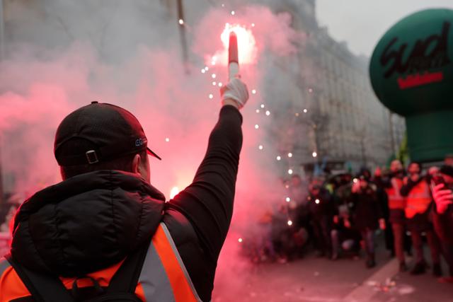 19일(현지시간) 프랑스 전역에서는 에마뉘엘 마크롱 프랑스 대통령이 추진하는 연금개혁에 반대하는 1차 총파업 겸 시위가 열렸다. 사진은 파리에서 한 참가자가 시위대를 향해 횃불을 들고 있는 모습. 파리=AP·연합뉴스