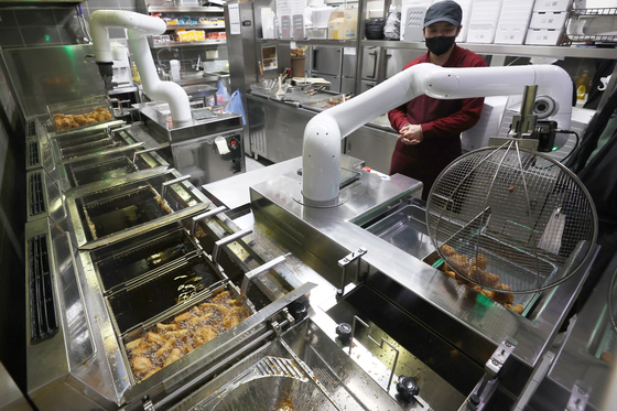 A chicken-frying robot performs its tasks at a Kyochon Chicken store in Dasan, Gyeonggi, on Jan. 25. [YONHAP]