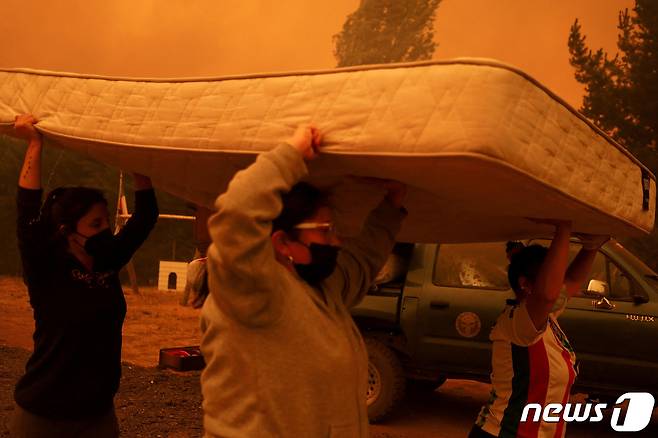 4일(현지시간) 칠레 콘셉시온 인근 산타후아나에서 주민들이 산불을 피해 침대 매트리스를 머리에 이고 대피하고 있다. ⓒ 로이터=뉴스1 ⓒ News1 권진영 기자
