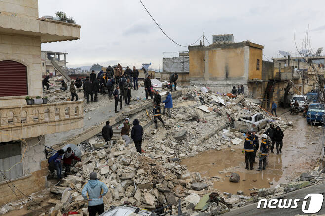 6일(현지시간) 시리아 잔다리스 마을에서 사람들이 지진으로 붕괴한 건물 잔해 속에서 희생자 및 생존자를 찾아 옮기고 있다. 강진 후 내린 비로 바닥엔 물이 가득 고였다. 시리아 정부는 통제 지역에서만 326명이 숨졌다고 발표했다. ⓒ 로이터=뉴스1 ⓒ News1 권진영 기자