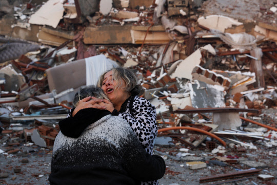 강진 발생 다음날인 7일(현지시간) 지진으로 붕괴한 튀르키예 하타이의 건물 잔해 앞에서 두 사람이 서로 끌어안고 있다. 전날 튀르키예에서 규모 7.8, 7.5의 강진이 잇따라 발생하고 80여 차례 여진이 일어나 튀르키예와 인접국 시리아에서 지금까지 4천명 이상이 사망했다. 여진은 이날 오전에도 발생했다.     하타이 로이터=연합뉴스