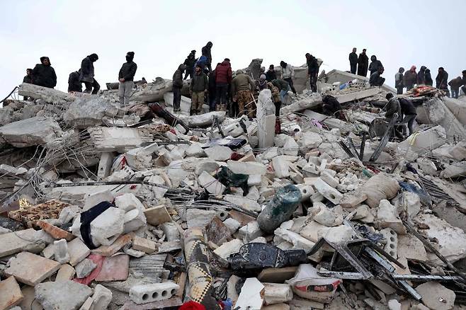 TOPSHOT - Residents and rescuers search for victims and survivors amidst the rubble of collapsed buildings following an earthquake in the village of Besnaya in Syria's rebel-held northwestern Idlib province on the border with Turkey, on February 6, 2022. - At least 1,293 people were killed and 3,411 injured across Syria today in an earthquake that had its epicentre in southwestern Turkey, the government and rescuers said. (Photo by OMAR HAJ KADOUR / AFP) /사진=연합 지면외신화상