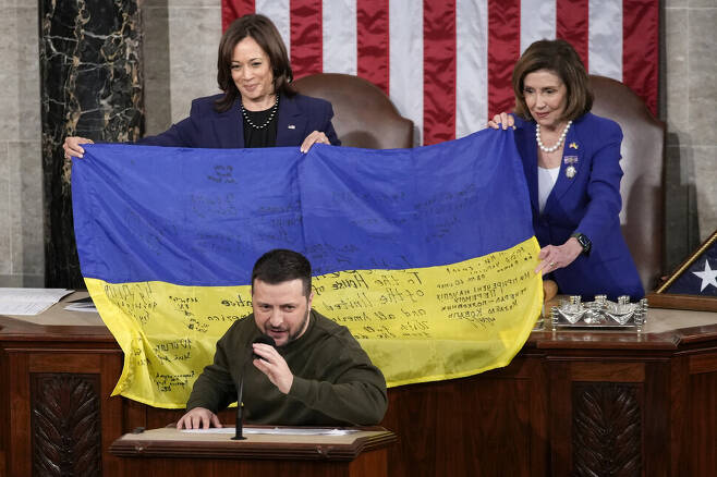 지난 21일 미국 워싱턴 국회의사당에서 볼로디미르 젤렌스키 우크라이나 대통령(아래)이 연설하는 가운데 카멀라 해리스 미국 부통령(뒤 왼쪽), 낸시 펠로시 하원의장이 우크라이나 국기를 들고 있다. AP 연합뉴스