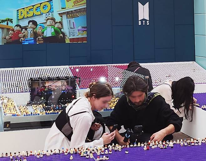 더현대 5층에 마련된 ‘레고 BTS Dynamite 팝업스토어’에서 방문객들이 디오라마 관람객석에 앉힌 미녀피겨를 촬영하고 있다. (사진=레고그룹)
