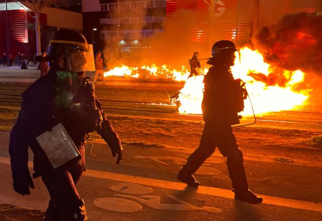 프랑스 파리에서 18일 연금개혁에 반대하는 시위대가 낸 것으로 추정되는 불길 사이로 경찰들의 모습이 보이고 있다. 파리=로이터 연합뉴스