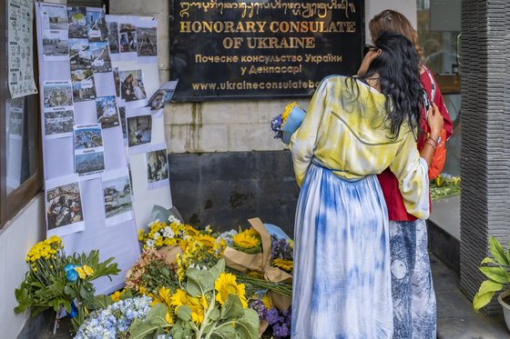 지난달 24일(현지시간) 인도네시아의 휴양지 발리 덴파사르에서 한 여성이 러시아의 침공 1년을 맞아 우크라이나 영사관 앞에 헌화하고 있다. AFP=연합뉴스