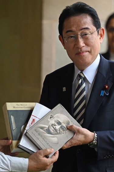기시다 후미오 일본 총리가 20일 인도 뉴델리에 있는 마하트마 간디 기념관을 찾아 그와 관련된 책을 선물받고 있다. 뉴델리/AFP 연합뉴스