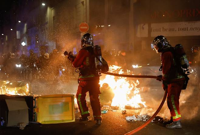 21일(현지 시각) 연금 개혁 반대 시위가 벌어지고 있는 프랑스 파리에서 소방대원들이 불타는 쓰레기에 소화액을 뿌리고 있다.