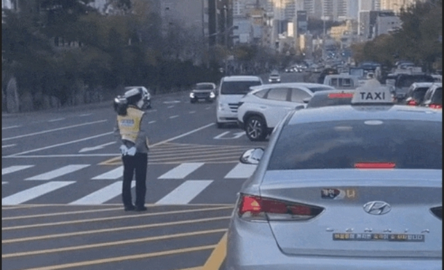 한 교통경찰이 서울 동작구 상도역 주변 도로에서 뒷짐을 진 채 근무를 서고 있다. 온라인 커뮤니티 캡처