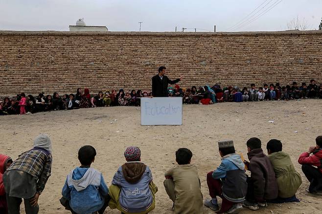 대학생인 교사인 와지르 칸이 칠판에 ‘교육’이라는 단어를 써 놓고 어린이들에게 이야기하고 있다. 카불/EPA 연합뉴스