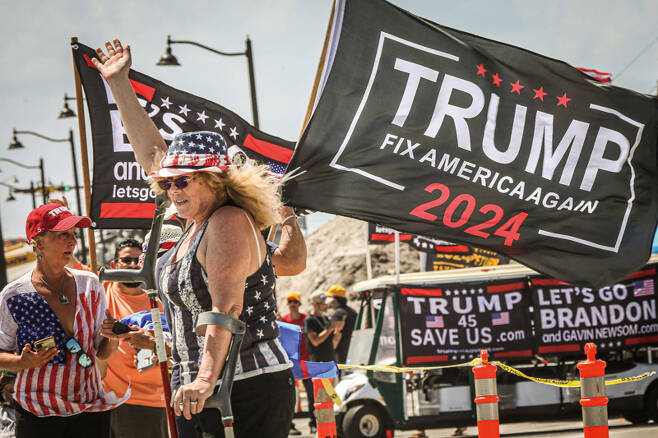 4월1일(현지시간) 미국 플로리다주 팜비치의 마러라고 리조트 인근에서 도널드 트럼프 전 대통령 지지자들이 '미국을 다시 고치자'라고 쓴 깃발을 흔들고 있다. ⓒAFP 연합