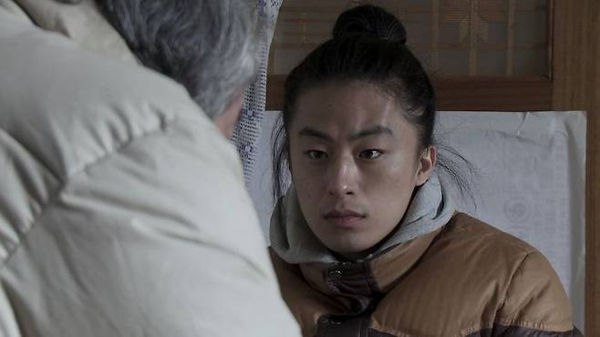 영화 '겨울잠'에서 구병으로 등장한 구교환. 낯선 할배 조송(문창길 분)이 자신을 자꾸 아들이라 부르고 이웃들에게도 아들이라 소개하는 상황에 처한 구병의 모습 ⓒ출처=네이버 영화 포토